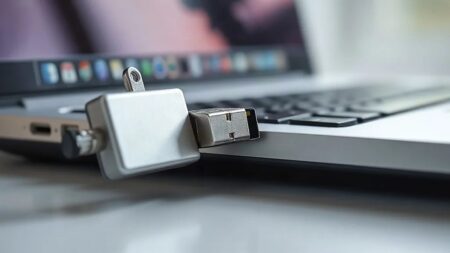 Dizüstü bilgisayarın yan portundan yarı çıkarılmış metal USB bellek; Windows USB geçmişine kaydolan depolama aygıtı (Temsili görsel)